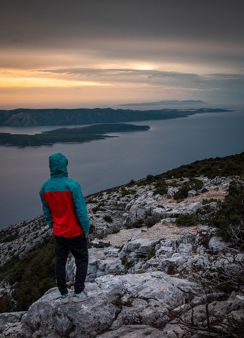 Mann stehend mit Blick auf Insel Hvar von Aussichtspunkt Vidova Gora auf Brac bei Sonnenuntergang, Kroatien\n