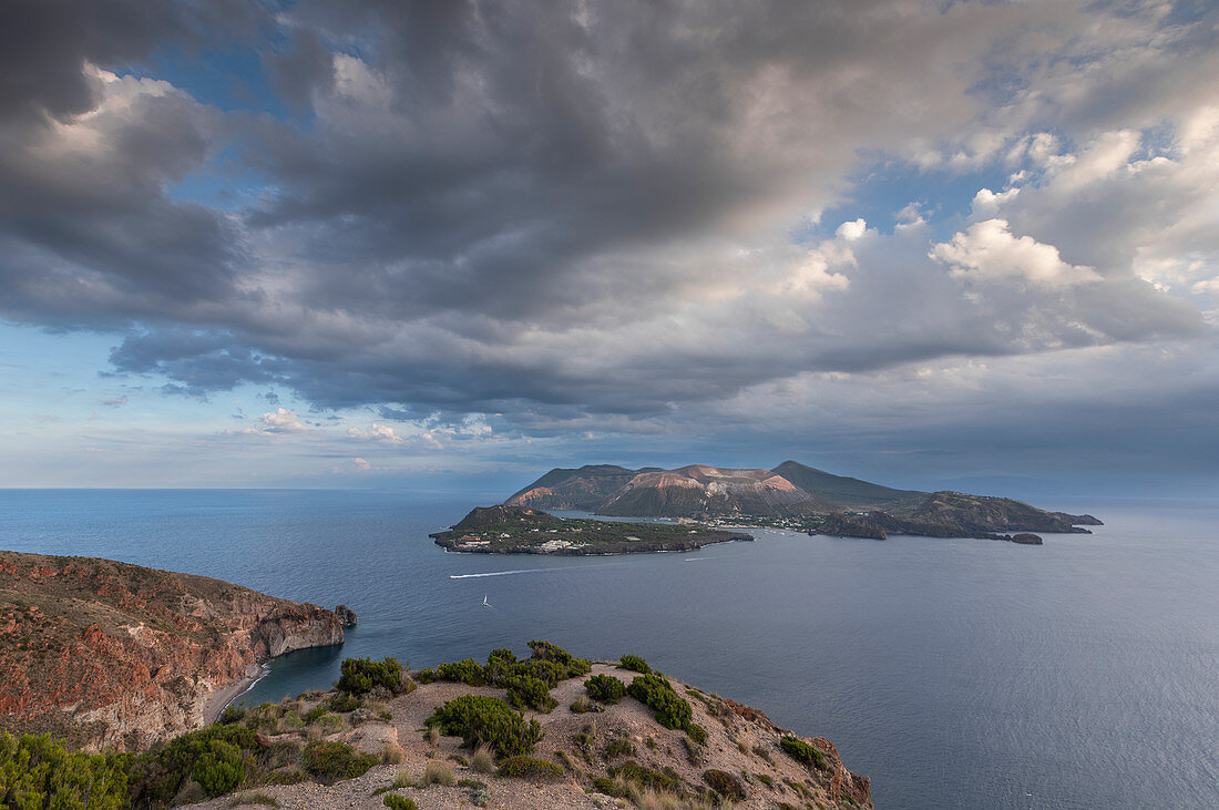 Lipari coastline with view of Vulcano volcanic island with dramatic clouds, Sicily Italy
