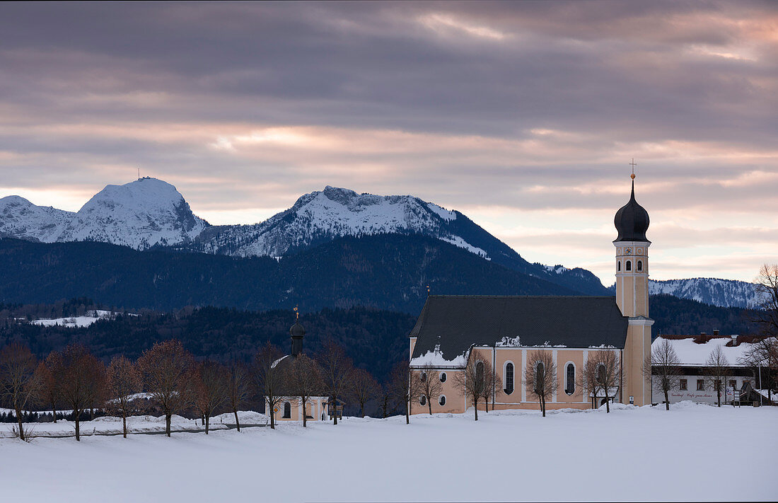 Wallfahrtskirche Wilparting am Irschenberg mit Schnee im Winter im Sonnenaufgang, Berge im Hintergrund, Bayern