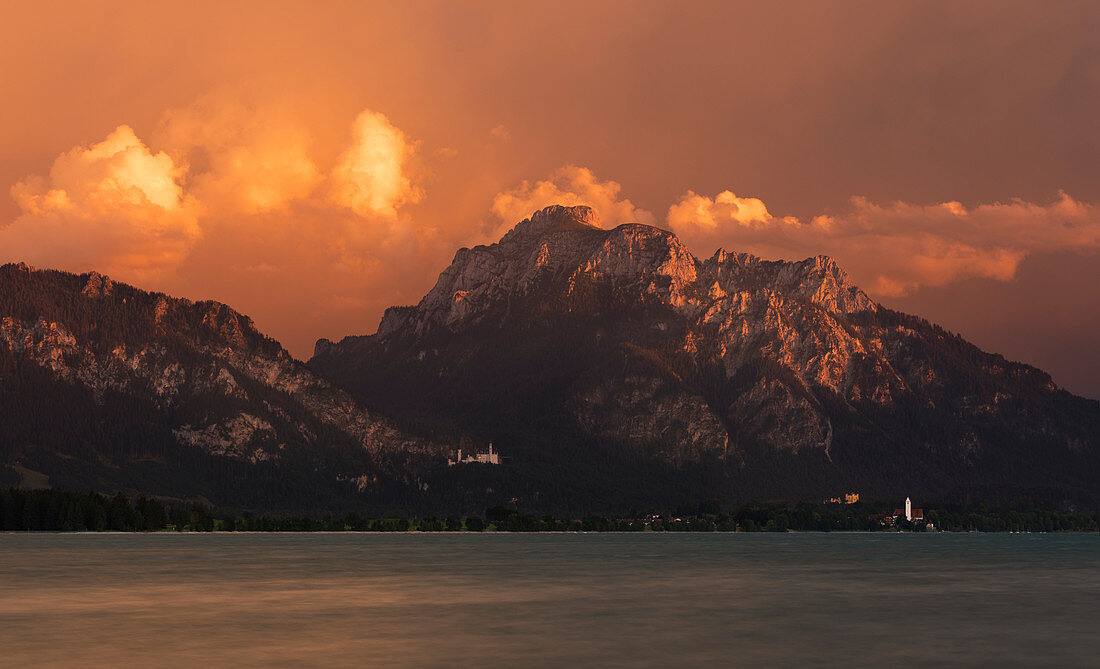 Schloss Neuschwanstein und Hohenschwangau am Forggensee im Ammergebirge mit Wolken, Sonnenuntergang, Bayern