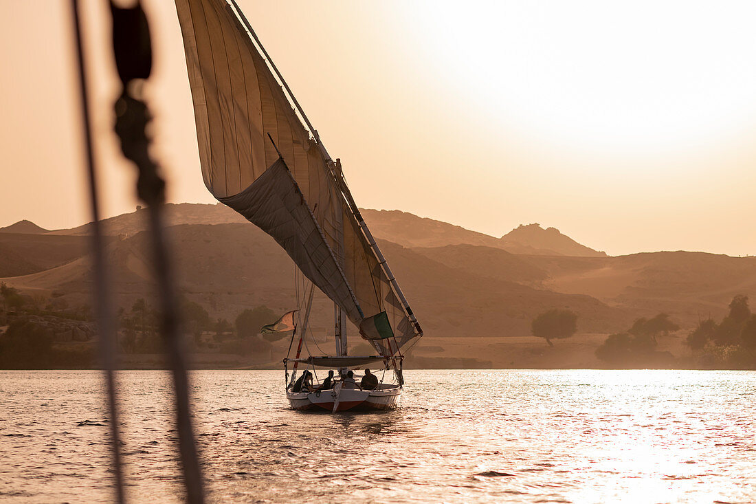 Ein traditionelles Felucca-Segelboot mit Holzmasten und Baumwollsegeln bei Sonnenuntergang auf dem Nil, Assuan, Ägypten, Nordafrika, Afrika