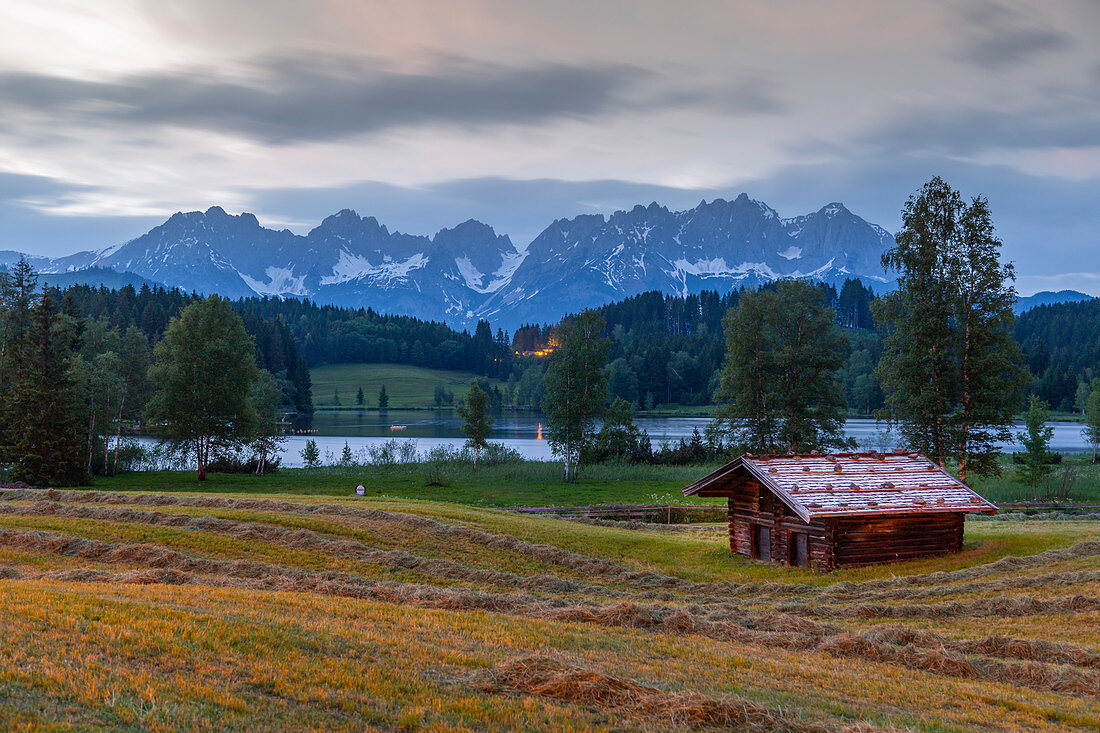 Blick auf traditionelle Blockhütte, im Hitergrund der Wilde Kaiser am Schwarzsee nahe Kitzbühel, Tirol, Österreich, Europa