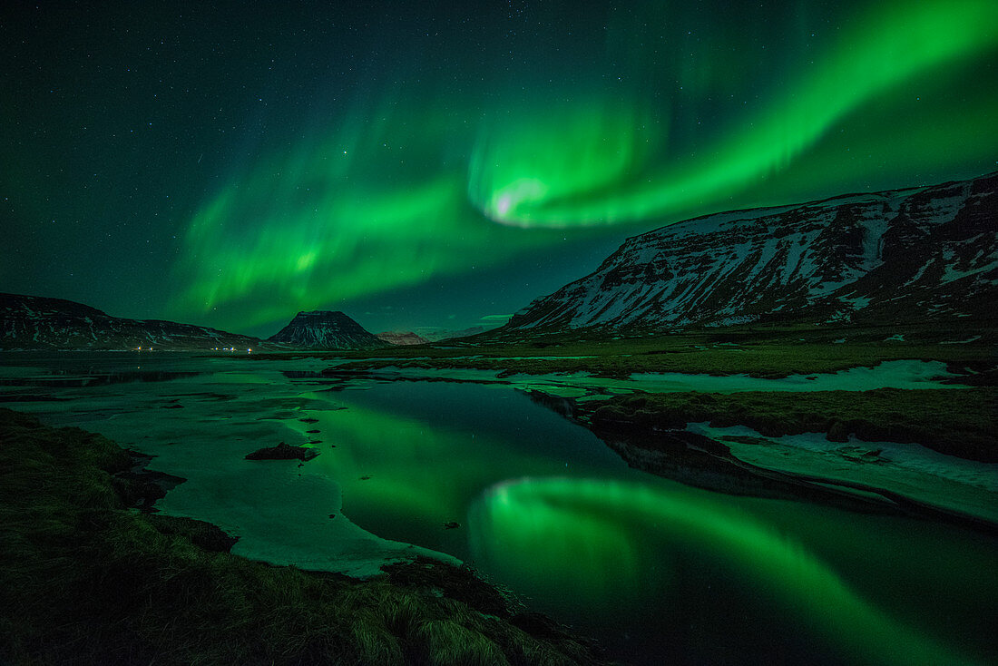 Aurora borealis (Northern Lights) reflected in partially frozen lake, North Snaefellsnes, Iceland, Polar Regions