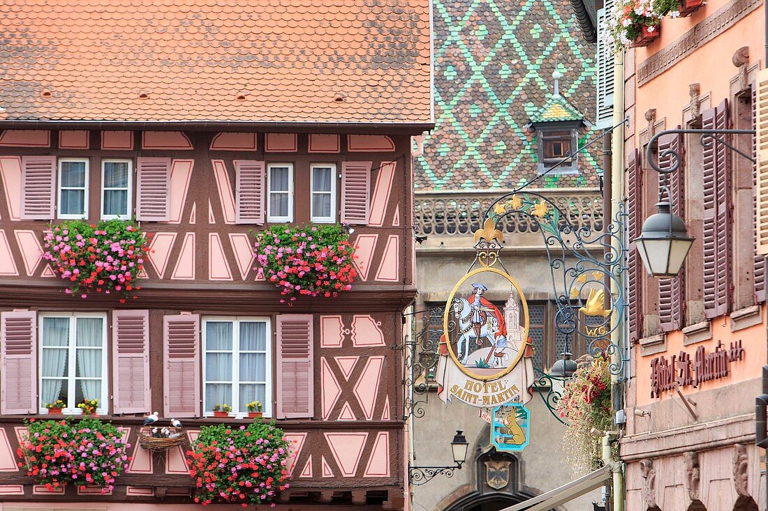 France, Haut Rhin, route des Vins d'Alsace, Colmar, facades and hotel sign of Hotel Saint Martin in Grand Rue, tiled roof of former custom building in the background