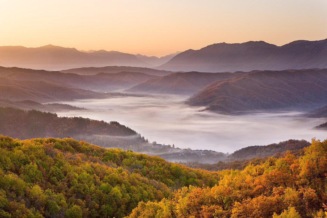 Looking down onto the little Zagorian village of Kipi on a misty morning in Autumn, just after sunrise, Epirus, Greece, Europe