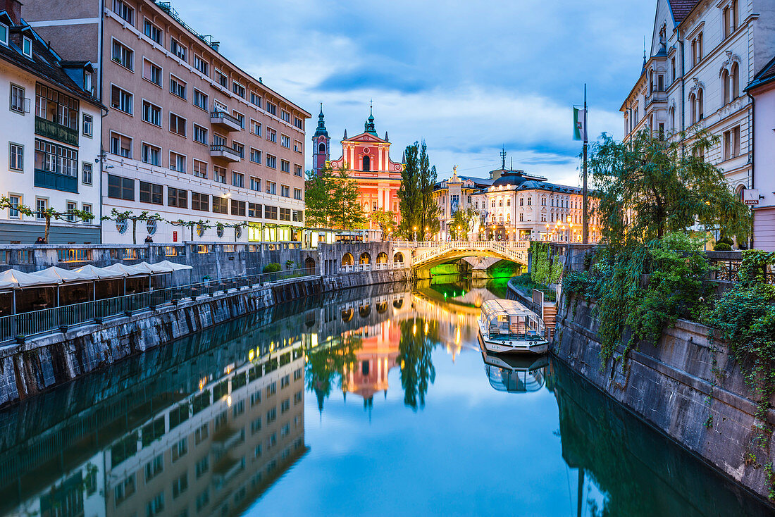 Ljubljana triple bridge and the Franciscan Church of the Annunciation reflected in Ljubljanica River at night, Lubljana, Slovenia, Europe