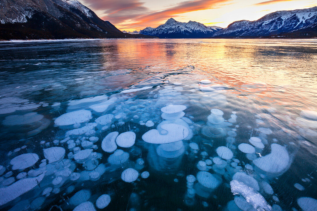 Blasen im Eis des Abraham Lake, Elliot Peak im Hintergrund bei Sonnenuntergang, Alberta, Kanada, Nordamerika