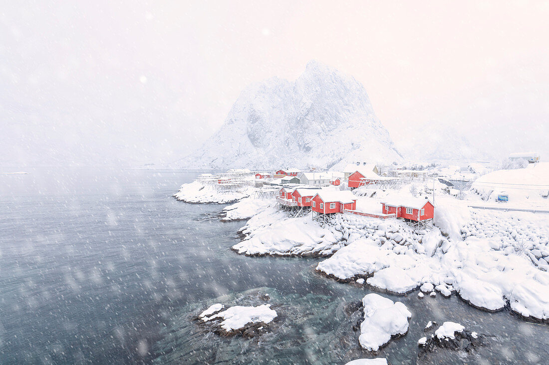 Starker Schneefall über den Fischerhäusern namens Rorbu, umgeben von gefrorenem Meer, Hamnoy, Lofoten, Arktis, Norwegen, Skandinavien, Europa