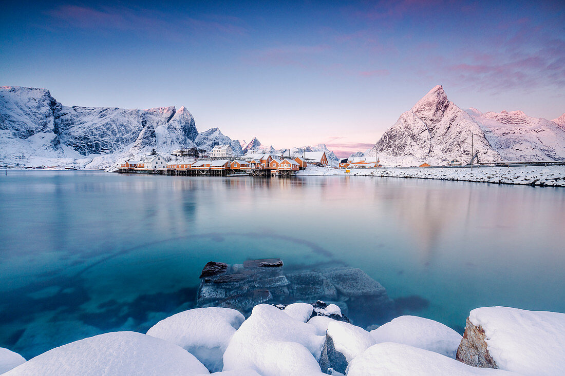 Die Farben der Morgendämmerung umrahmen die Fischerhäuser, umgeben von gefrorenem Meer, Sakrisoy, Reine, Nordland, Lofoten, Arktis, Norwegen, Skandinavien, Europa