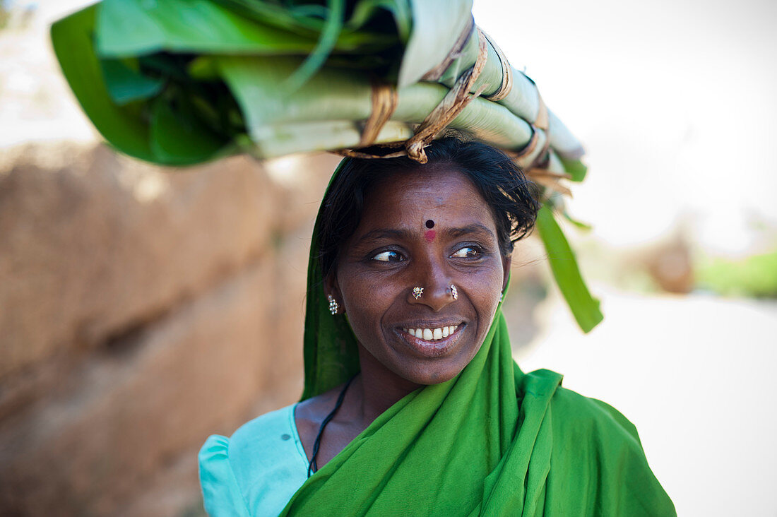 Eine Frau trägt aufgerollte Bananenblätter, die zum Einwickeln von Lebensmitteln verwendet werden, Karnataka, Indien, Asien
