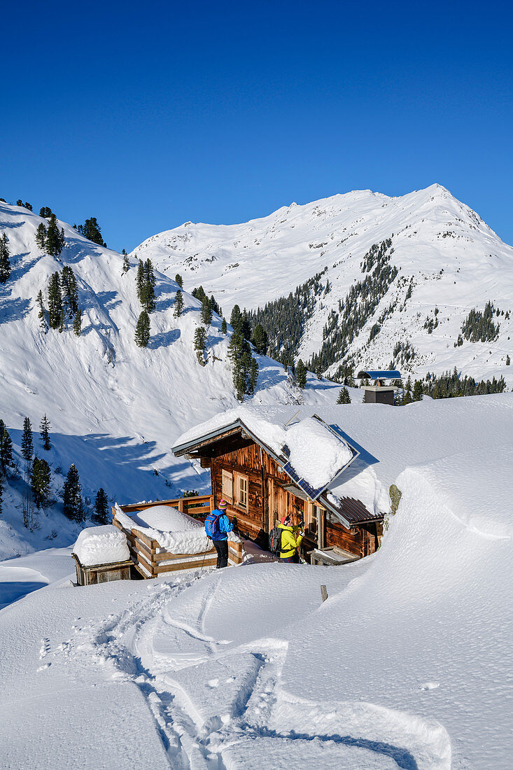 Mann und Frau auf Skitour machen an Alm Pause, Regenfeldjoch, Kitzbüheler Alpen, Tirol, Österreich