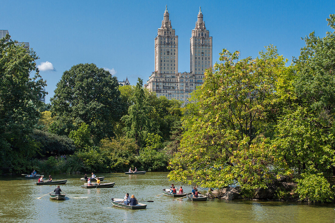 ROWERS ROWING A BOAT ON THE LAKE IN CENTRAL PARK WITH THE TWO TOWERS OF THE SAN REMO APARTMENT BUILDING IN THE BACKGROUND, MANHATTAN, NEW YORK CITY, NEW YORK, UNITED STATES, USA