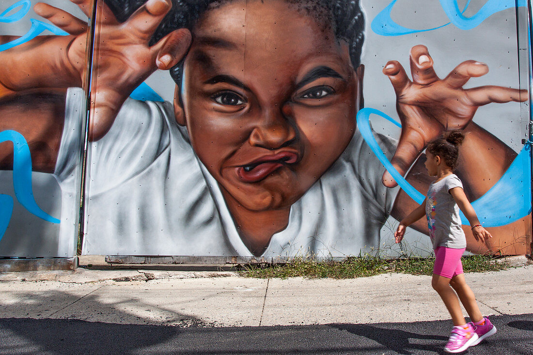 YOUNG AFRO-AMERICAN GIRL PASSING IN FRONT OF A WALL COVERED WITH A MURAL IN THE NEIGHBORHOOD OF BUSHWICK, BROOKLYN, NEW YORK CITY, NEW YORK, UNITED STATES, USA