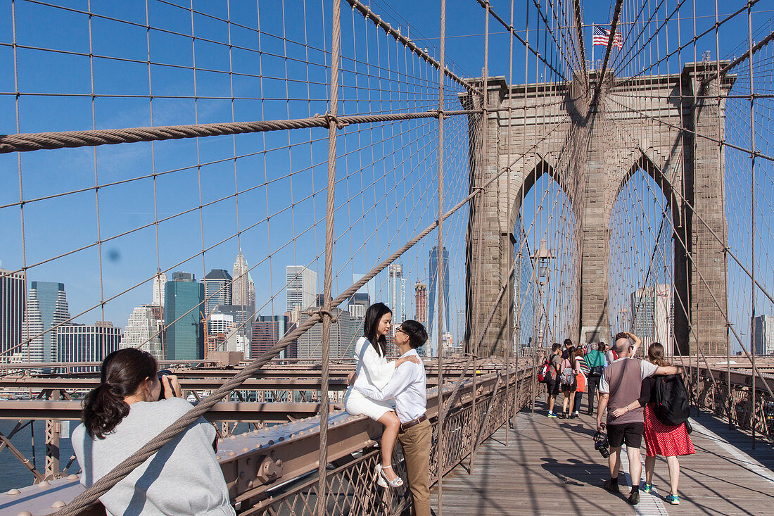 YOUNG CHINESE NEWLYWEDS HAVING THEIR PICTURE TAKEN BY A WEDDING PHOTOGRAPHER ON THE BROOKLYN BRIDGE WITH THE MANHATTAN SKYLINE AND ONE WORLD TRADE CENTER IN THE BACKGROUND, BROOKLYN BRIDGE, ARCHITECTURE, MONUMENT, NEW YORK CITY, NEW YORK, UNITED STATES, USA