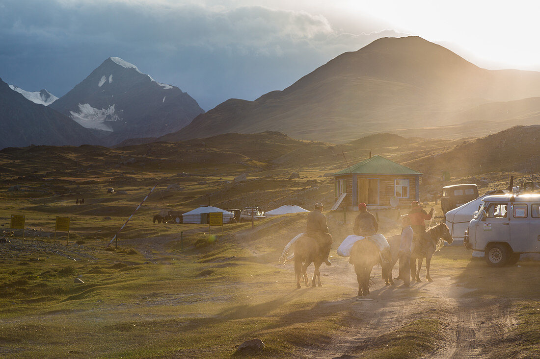 Reiter in der Nähe eines Grenzpostens bei Sonnenuntergang, Jurte und Altai-Massiv im Hintergrund, Provinz Bajan-Olgii, Mongolei