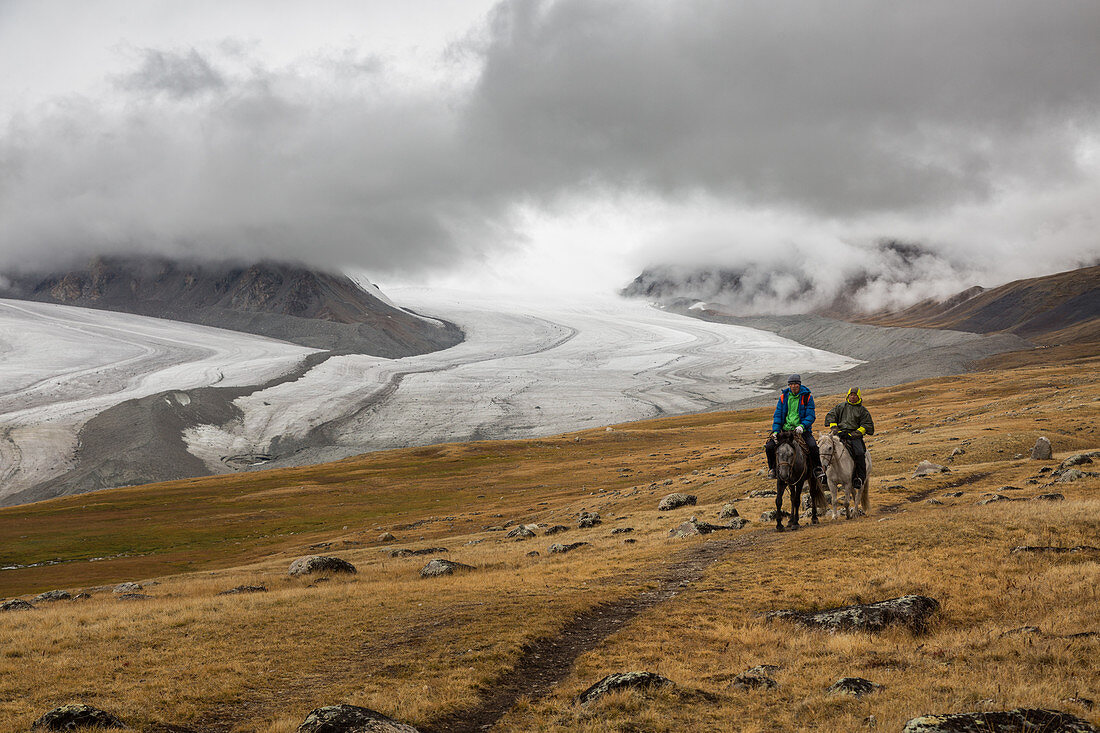 Mongolischer Reiter führt seinen Kunden im Altai-Gebirge, im Hintergrund die Gletscher Potanine und Alexander III, Provinz Bayan-Olgii, Mongolei