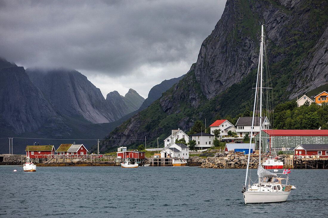 Segelboot und Traditionelle rote Holzhäuser, das Dorf Reine, Vestfjord, Lofoten, Norwegen
