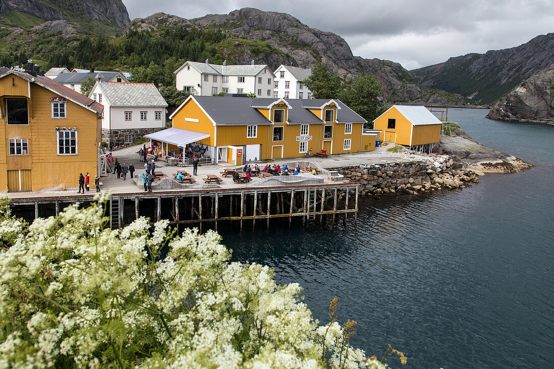 FISHING PORT WITH ITS TRADITIONAL FISHERMEN'S HOUSES OF YELLOW-PAINTED WOOD SURROUNDED BY MOUNTAINS, NUSFJORD, VESTFJORD, LOFOTEN ISLANDS, NORWAY