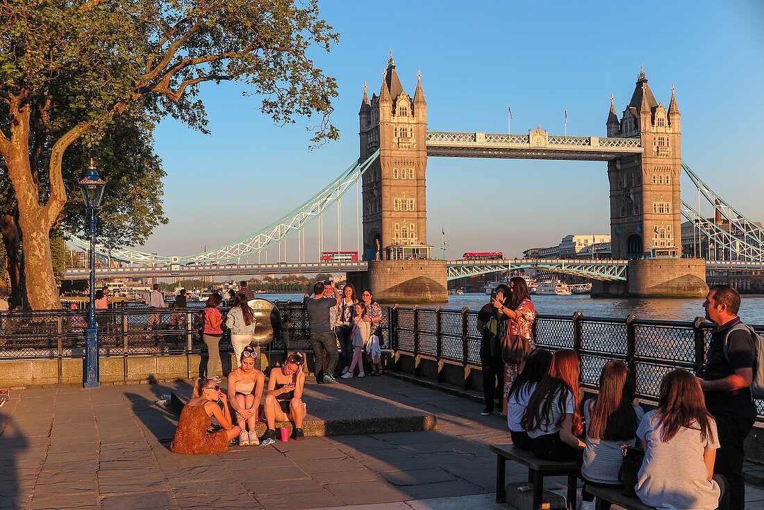 GROUP OF PEOPLE ON THE BANKS OF THE THAMES IN FRONT OF TOWER BRIDGE, LONDON, GREAT BRITAIN, EUROPE
