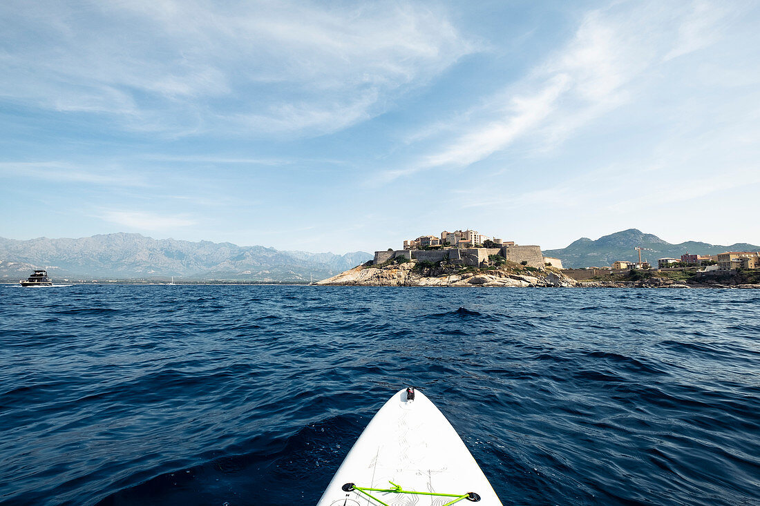 Blick von einem Stand-up-paddle-board auf die Zitadelle von Calvi, Korsika, Frankreich