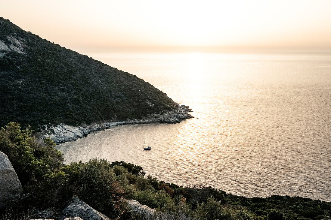 Segelboot bei Sonnenuntergang in einer Bucht bei Calvi, Korsika, Frankreich