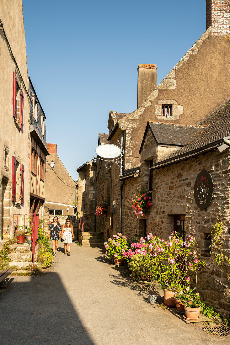 Zwei Frauen spazieren durch Gasse mit Steinhäusern und Blumen, La Roche-Bernard, Vilaine, Departement Morbihan, Bretagne, Frankreich, Europa