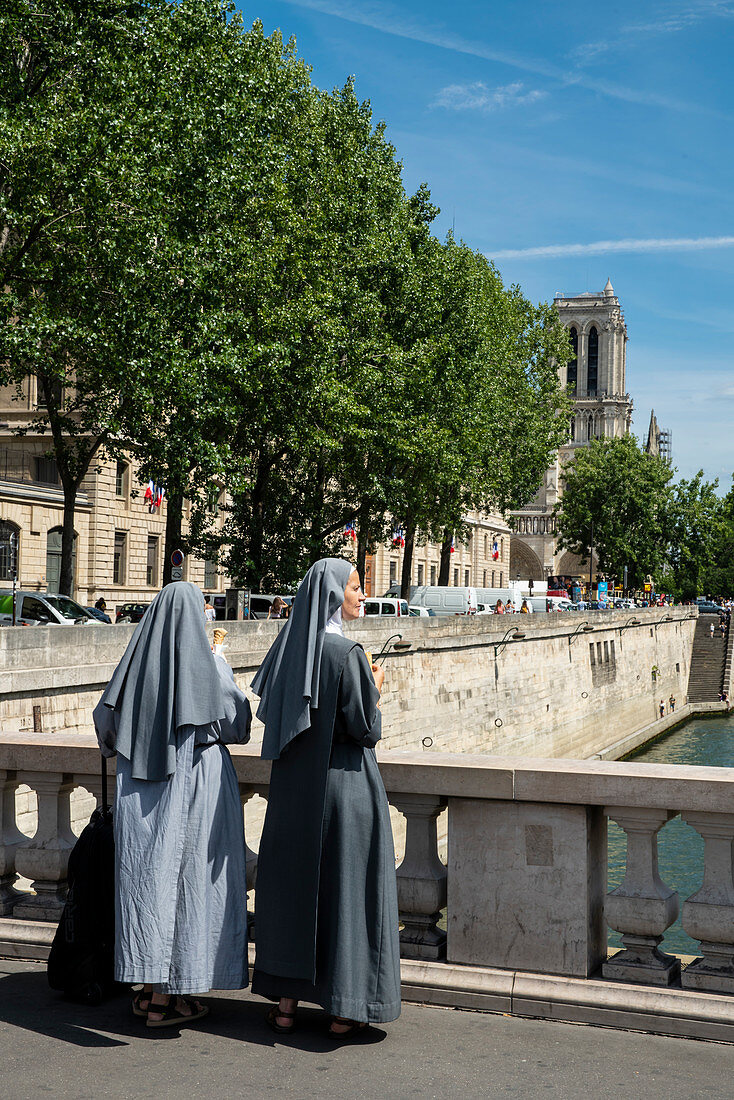 Zwei Nonnen essen Eis und blicken von Pont Saint-Michel zur Kathedrale Notre-Dame, Paris, Frankreich, Europa