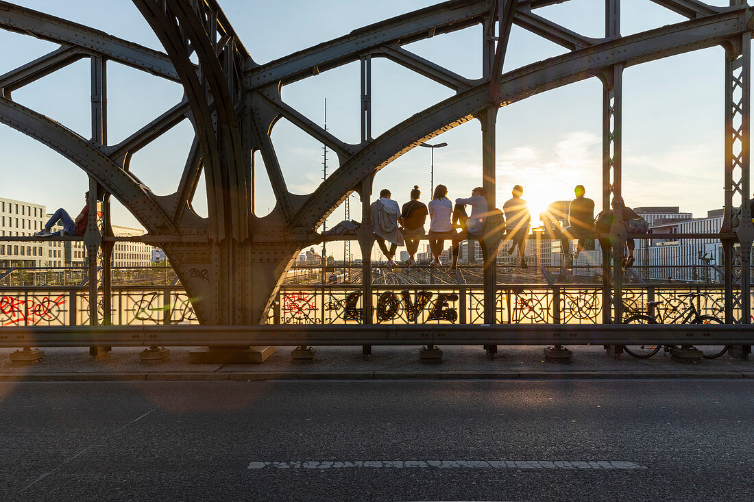 People sit at sunset on the Hackerbruecke in Muenchen, Bavaria, Germany, Europe