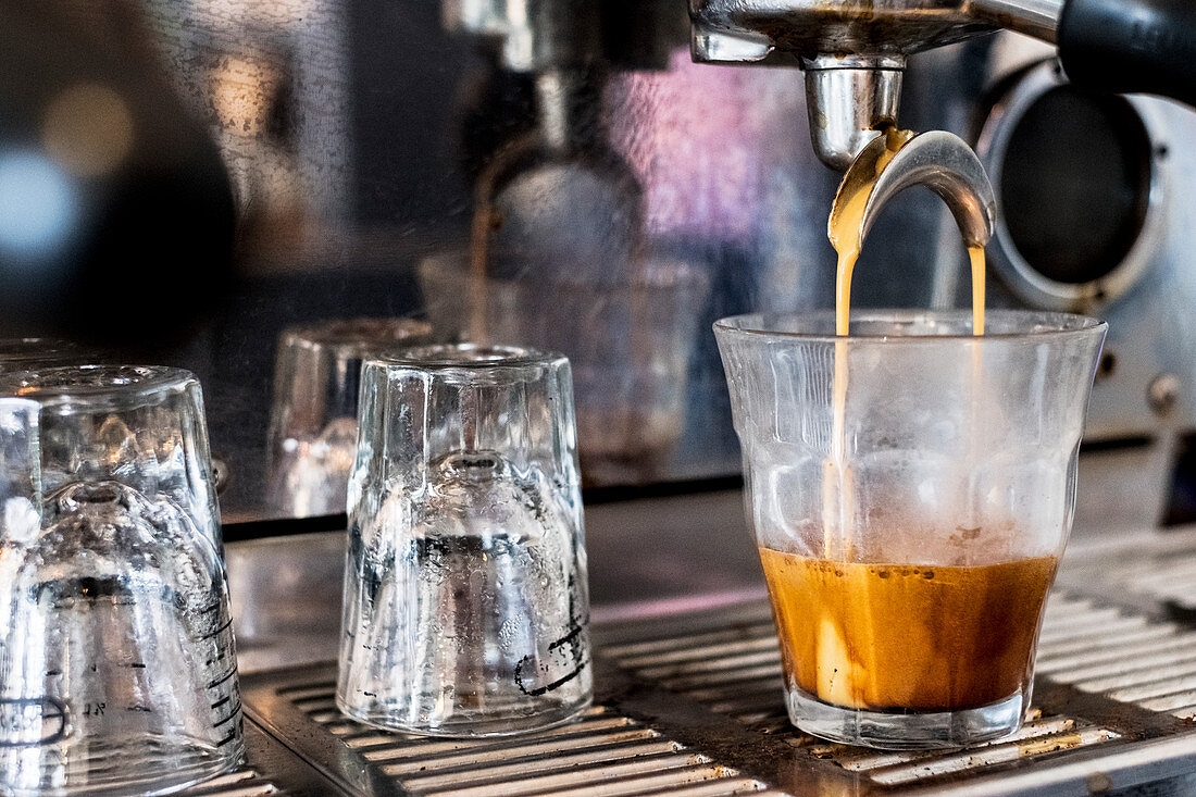 A commercial expresso machine in a coffee shop making an expresso shot.