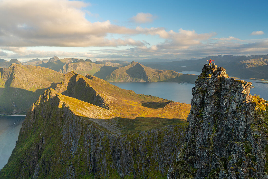 Man standing at the top of a pinnacle with a view over the landscape, Senja Island, Troms