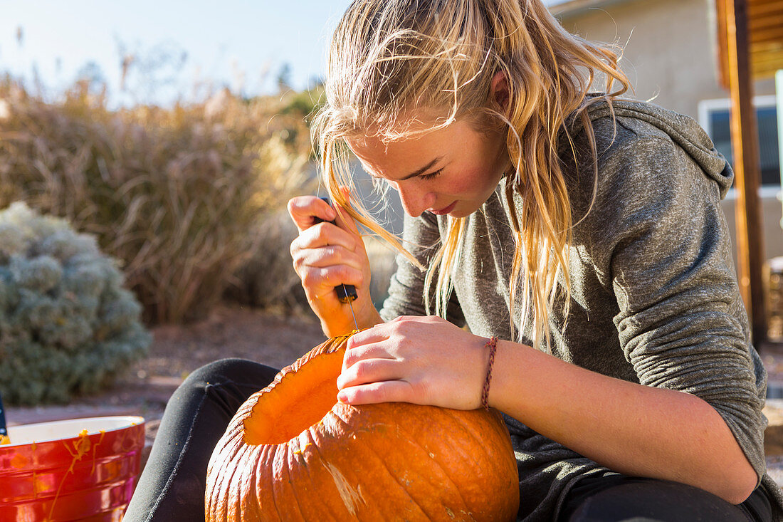 A teenage girl carving a pumpkin at Halloween,