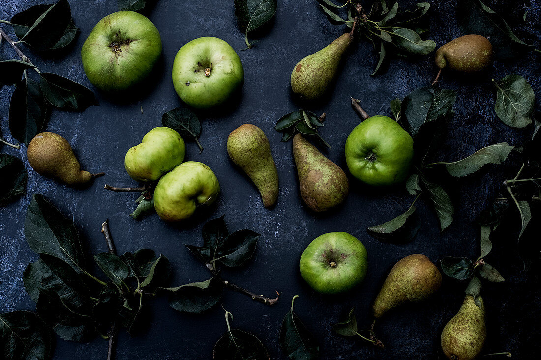 Grüne Birnen und Bramley-Äpfel auf schwarzem Hintergrund
