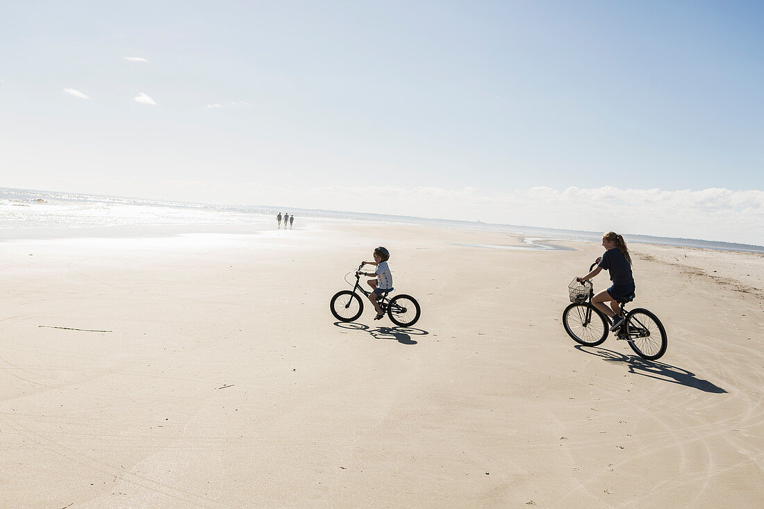 Junge und Mädchen radeln am offenen Strand