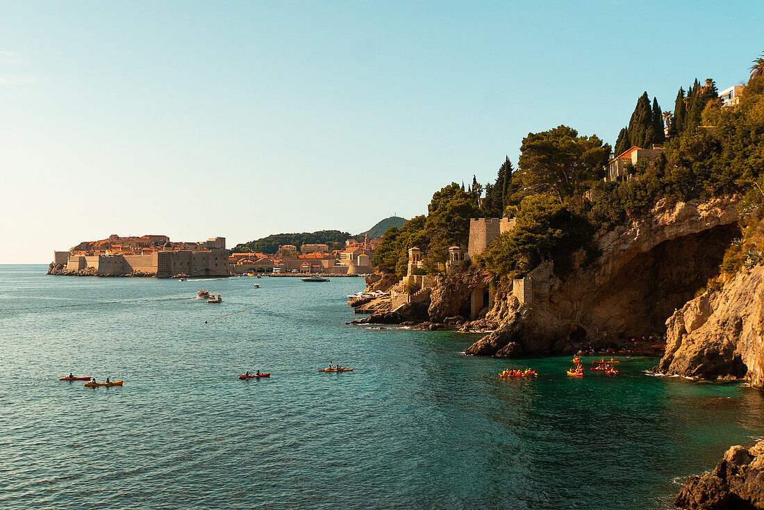 People kayaking in sea by rock formations, Dubrovnik, Croatia