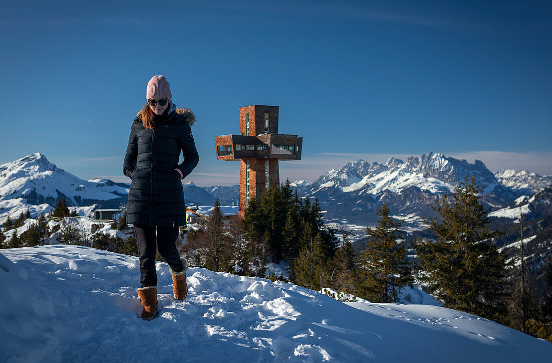 Frau mit Mantel und Mütze wandert am Jakobskreuz in Fieberbrunn Wilder Kaiser bei Winter, Tirol, Österreich