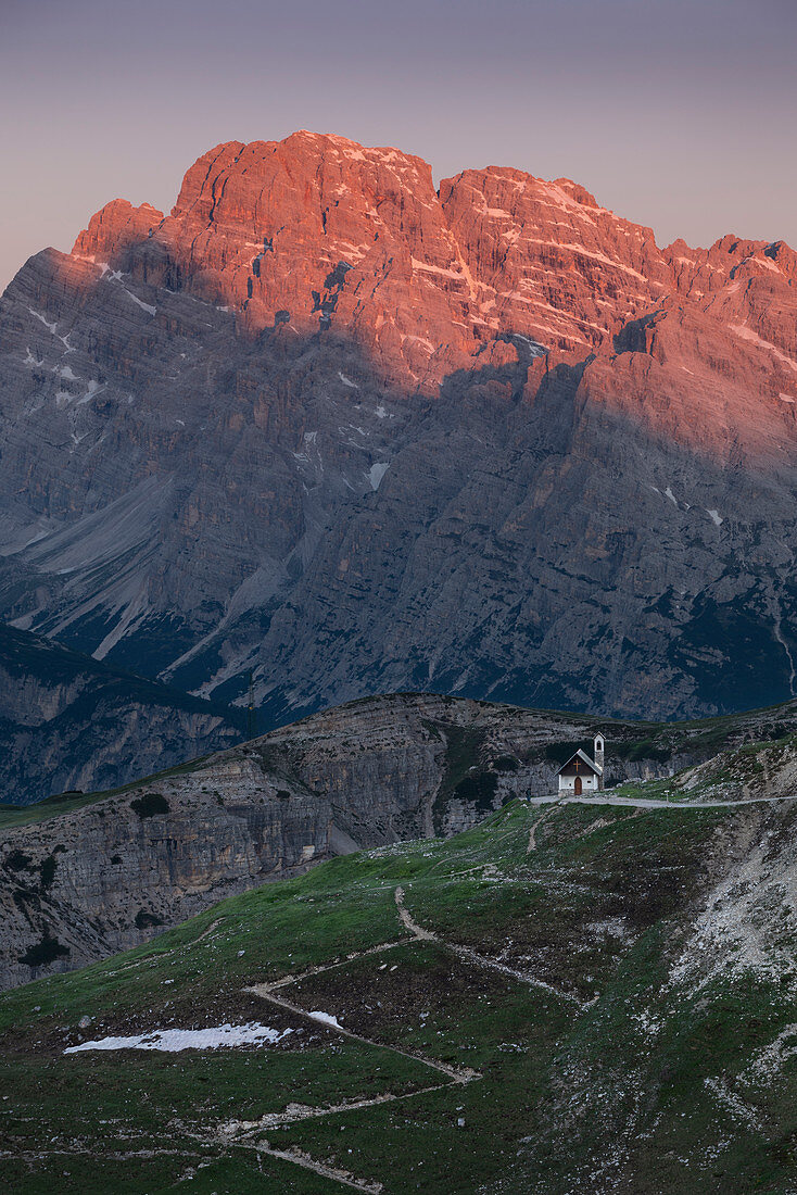 Sunrise over mountain landscape in the Dolomites below the Drei Zinnen with chapel and path, South Tyrol