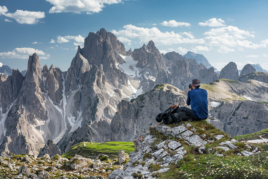 Man photographs mountain landscape in the Dolomites below the Lavardo hut at the Drei Zinnen a day, South Tyrol