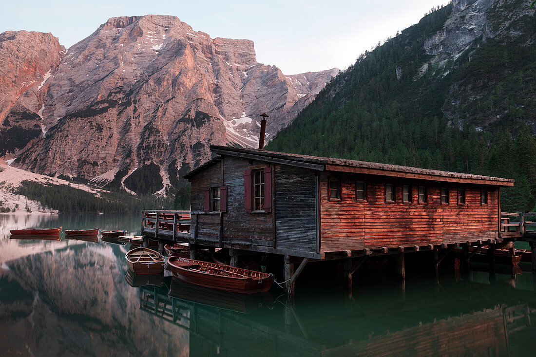 Boathouse with boats on Lake Braies at sunset in the Dolomites, South Tyrol