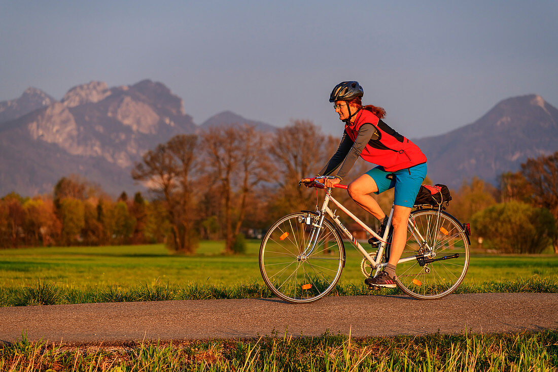 Frau beim Radfahren mit Heuberg im Hintergrund, Baum-zu-Baum-Radweg, Bad Feilnbach, Oberbayern, Bayern, Deutschland