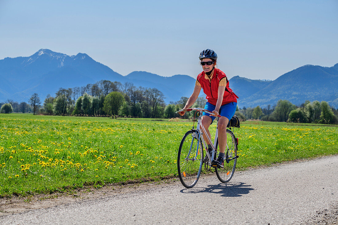Frau beim Radfahren mit Hochgern im Hintergrund, Chiemseeradweg, Chiemgau, Oberbayern, Bayern, Deutschland