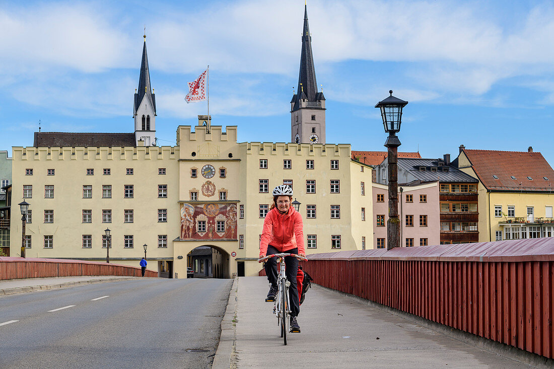 Frau beim Radfahren vor Innbrücke und Stadttor von Wasserburg, Wasserburg, Benediktradweg, Oberbayern, Bayern, Deutschland