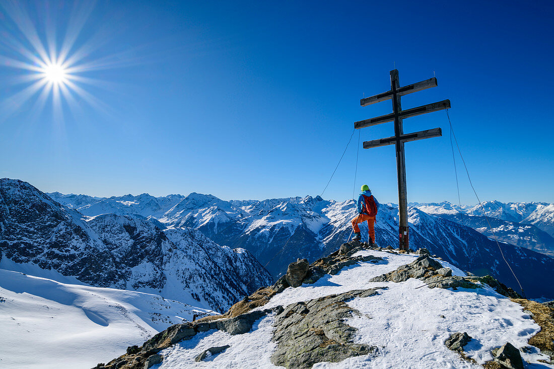 Frau auf Skitour steht am Kreuz des Wetterkreuzkogel, Ötztaler Alpen im Hintergrund, Wetterkreuzkogel, Stubaier Alpen, Tirol, Österreich 