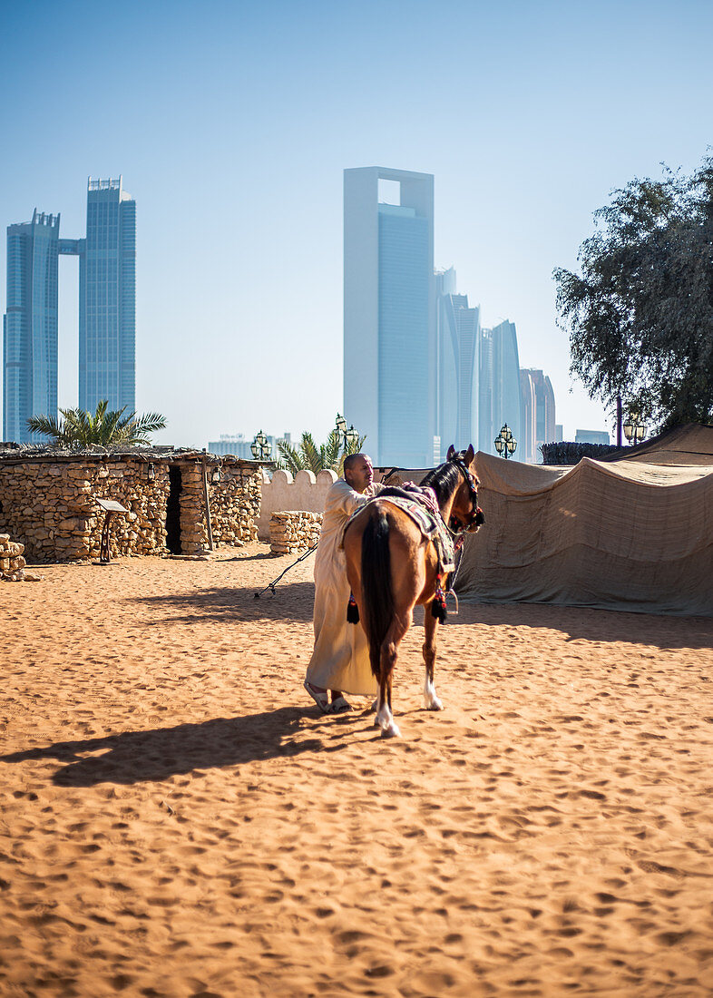 Einheimischer sattelt ein Pferd im Heritage Village in Abu Dhabi, VAE