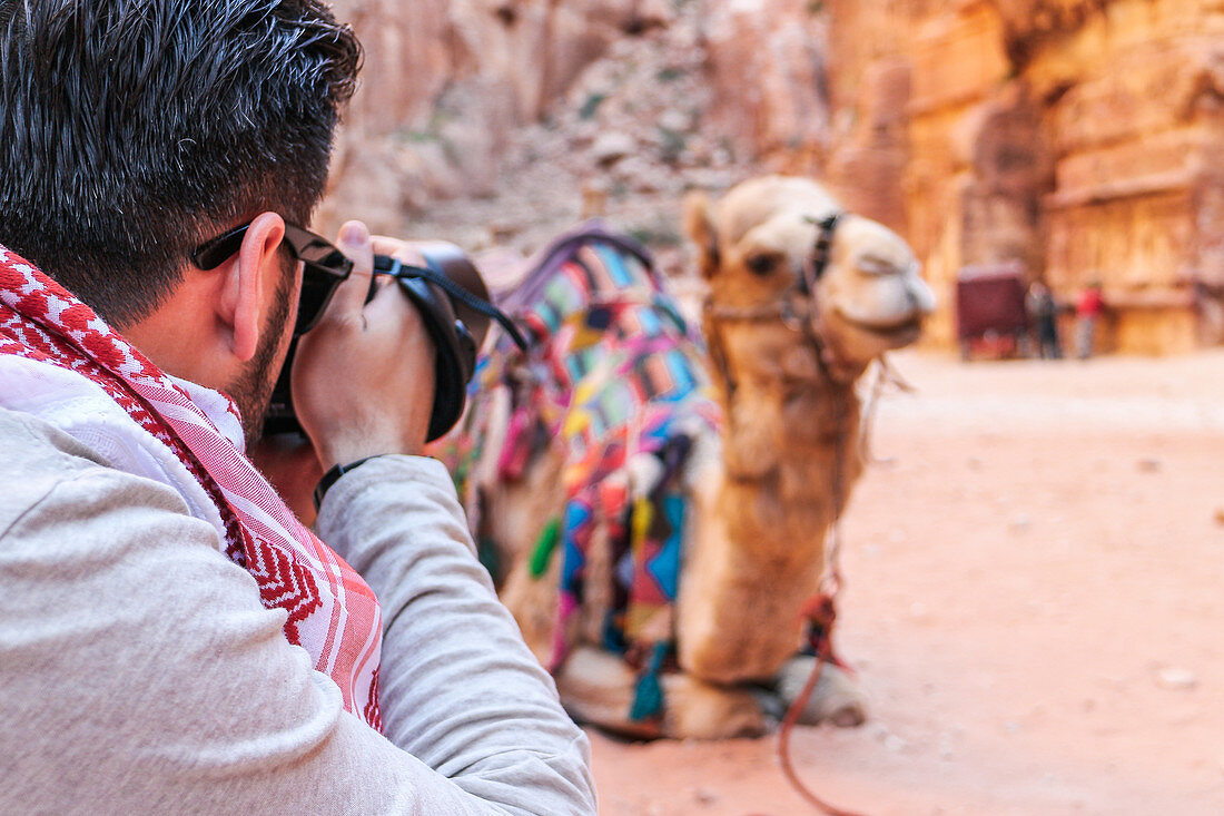 Tourist fotografiert ein Kamel in Petra, Jordanien