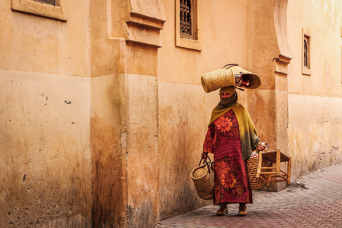 Frau trägt verschiedene Dinge durch die Straßen der Medina von Marrakesch, Marokko