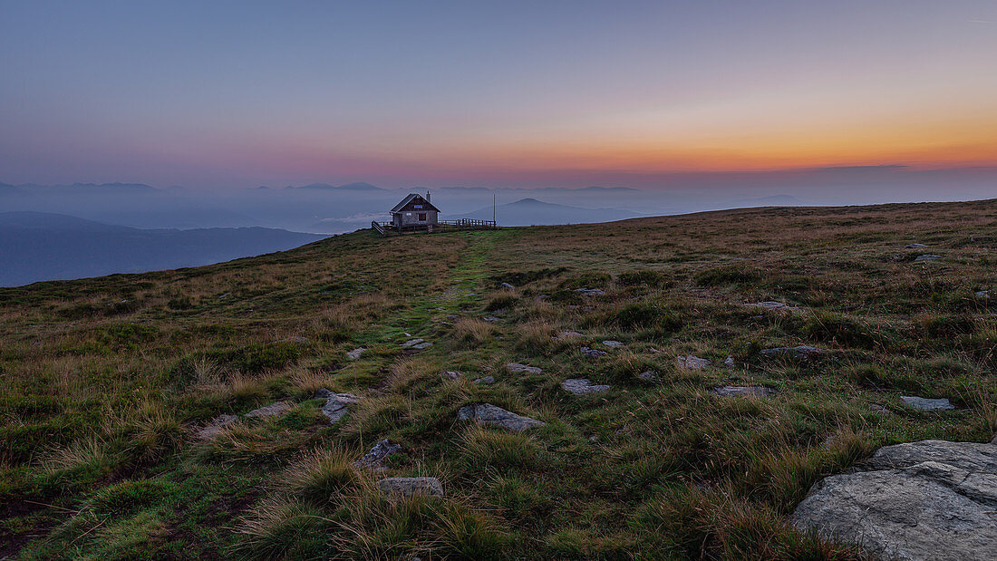 Early in the morning just before sunrise at the summit of the Frauenalpe with a view of the Murauer Hütte, Murau, Austria