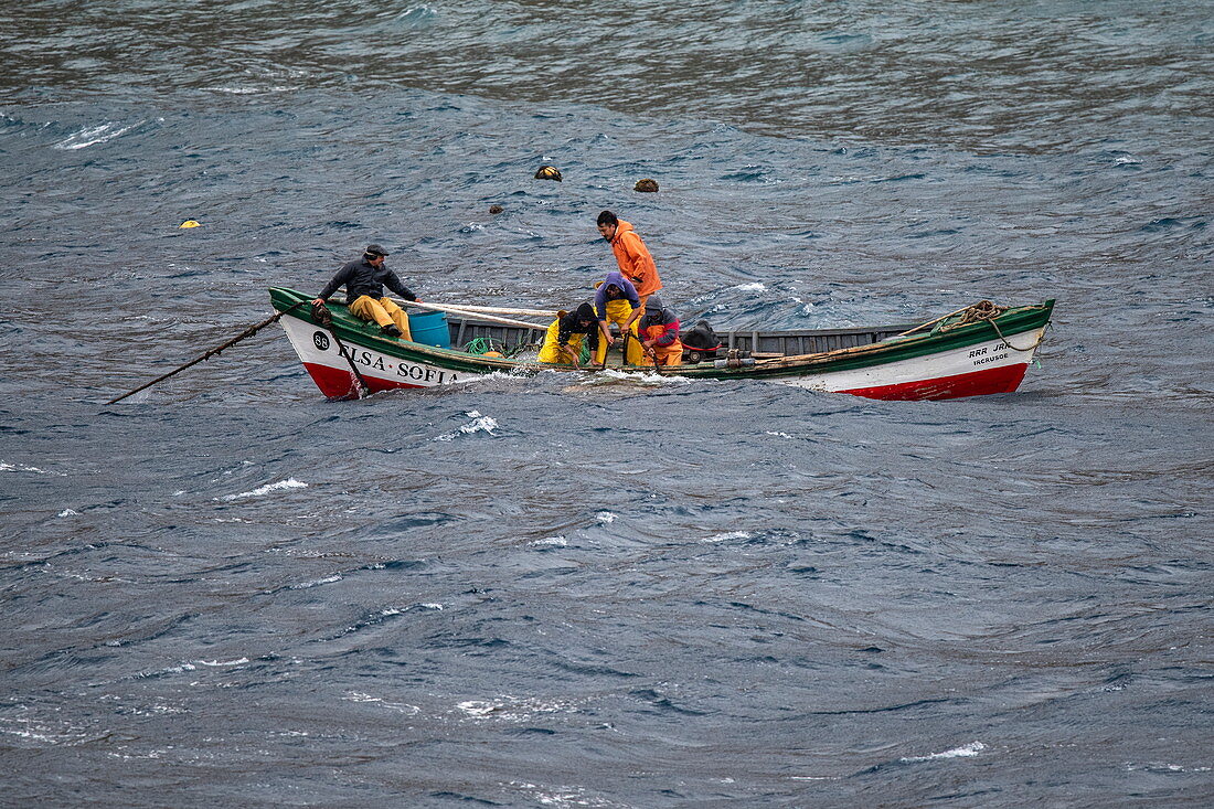 Ein kleines Fischerboot von der Insel trotzt rauer See, um sich einem besuchenden Expeditionskreuzfahrtschiff zu nähern, Alejandro Selkirk Island, Juan Fernández Islands, Chile, Südamerika