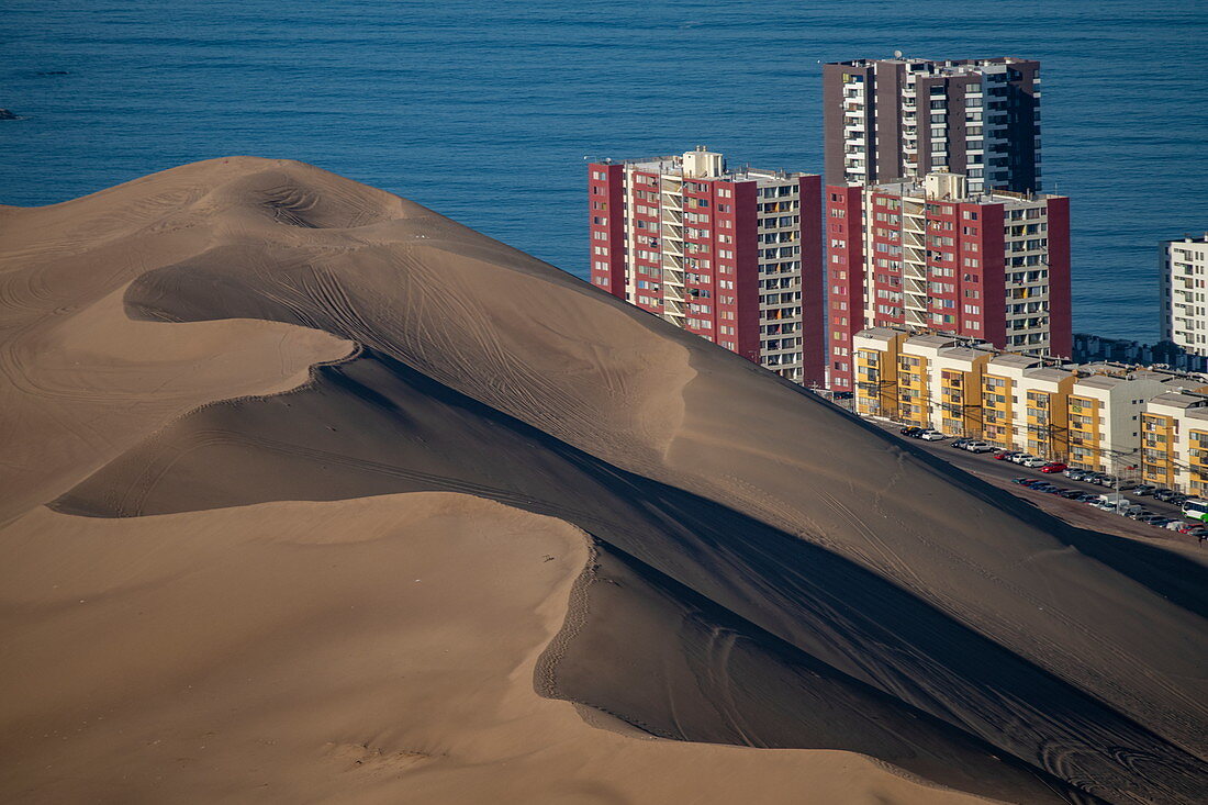 Eine massive Sanddüne und Hochhäuser an der Küste, gesehen von der Binnenstraße, nahe Iquique, Tarapaca, Chile, Südamerika