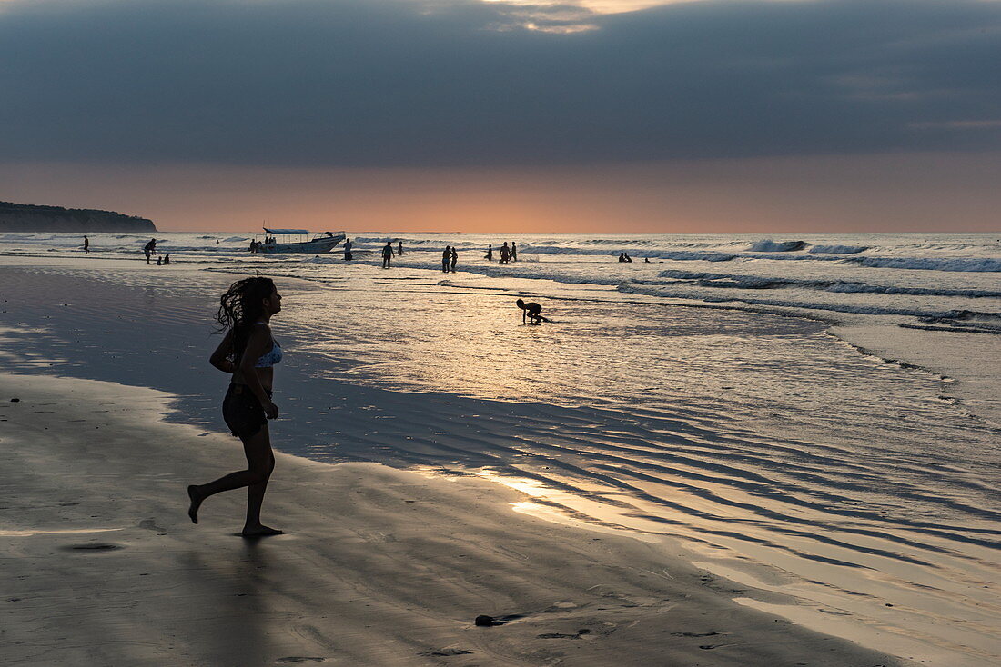 Eine junge Frau läuft auf einem breiten Strandabschnitt bei Ebbe am späten Nachmittag, Manta, Manabi, Ecuador, Südamerika