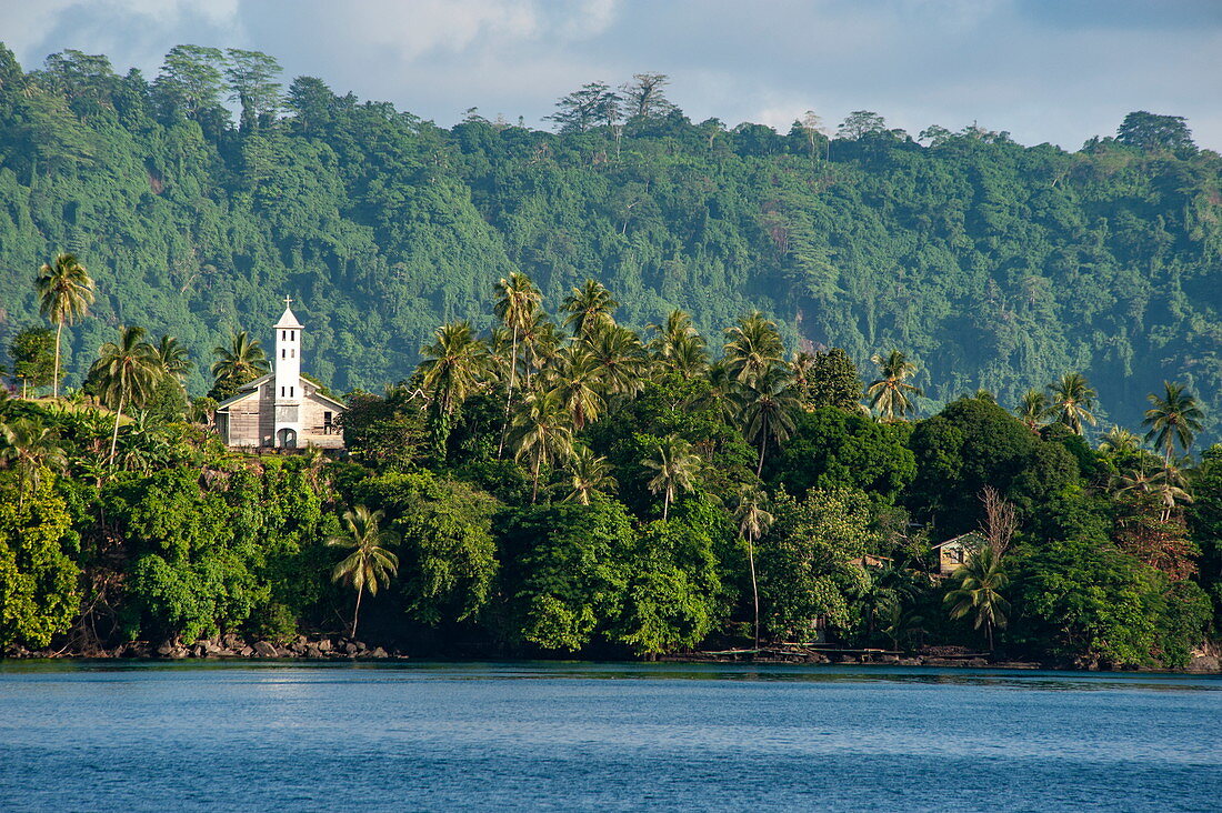 A lonely church stands on a crest surrounded by lush vegetation over the water, Garove Island, Vitu Islands, West New Britain Province, Papua New Guinea, South Pacific